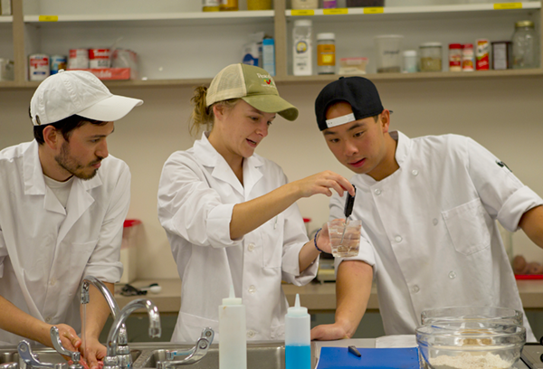 Three students taking water temperature in food lab
