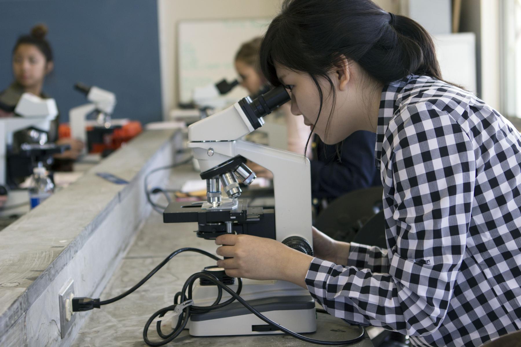 A student looking through microscope